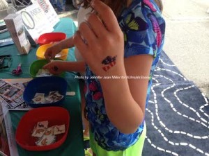 A child shows off their temporary tattoo of a dove that they applied at the Christ Community Church booth. Photo by Jennifer Jean Miller.