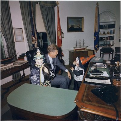 The senior John F. Kennedy smiles widely at the appearance of his daughter Caroline and son John Jr. on Halloween, 1963, less than a month before his assassination. NARA public domain image. 